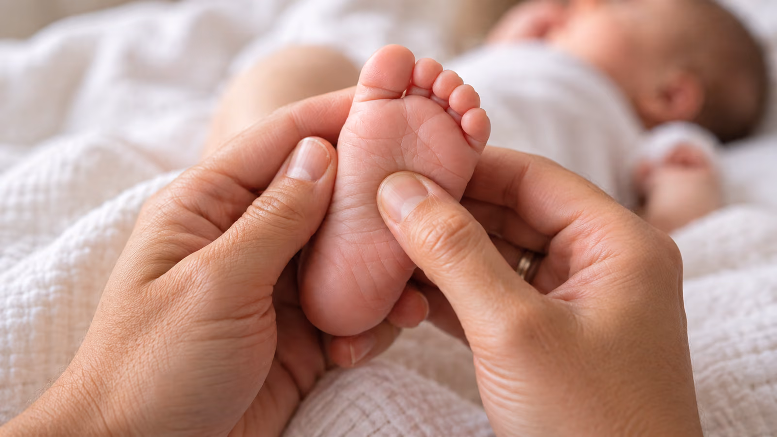 Elternhand hält behutsam den Fuß eines Babys